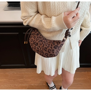 Gros plan d'un sac demi-lune imprimé léopard avec bandoulière porté par un mannequin
