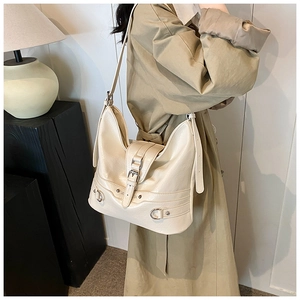 Detail view of cream PU leather shoulder bag with decorative straps and metal buckles