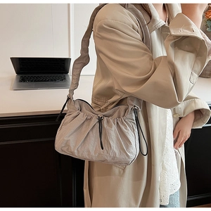 Dettaglio della borsa nuvola in nylon grigio chiaro con coulisse e tracolla su cappotto beige