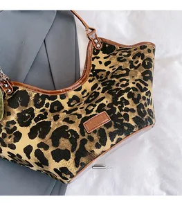 Détail du sac hobo en toile léopard avec bordures en cuir marron et bandoulière