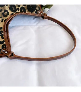 Détail du sac léopard avec poignées en similicuir marron et rivets métalliques argentés