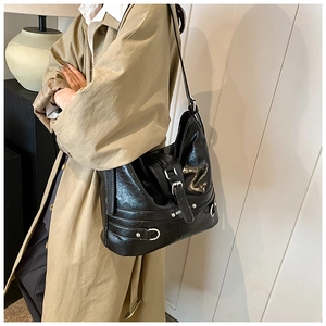 Detail of black crinkled leather tote bag with silver metal buckles and urban chic design