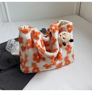 Detailstruktur der Plüsch-Tragetasche mit orangefarbenem Blumenmuster und Bärenanhänger