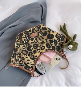 Détail du cabas en toile léopard avec bordure en cuir marron et pendentif grenouille