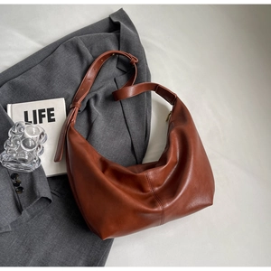 Detail of adjustable strap and caramel PU leather texture on minimalist hobo shoulder bag
