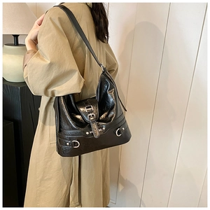 Detail of black glossy crinkled leather shoulder bag with silver metallic buckle hardware