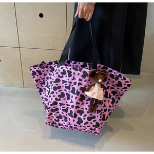 Dettaglio di una borsa tote in nylon con stampa mucca e ciondolo a forma di topo