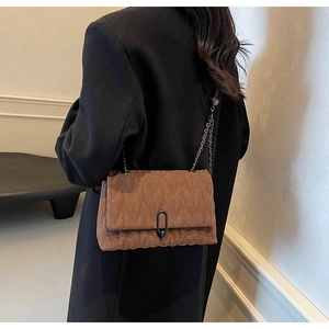 Detail view of brown quilted PU leather crossbody bag with chain strap and V-shaped stitching