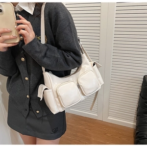 Close-up of white high-gloss PU leather shoulder bag with multi-pocket utility design