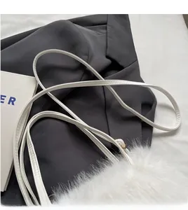 Detailed close-up of white plush shoulder bag with slim faux leather strap and neat stitching