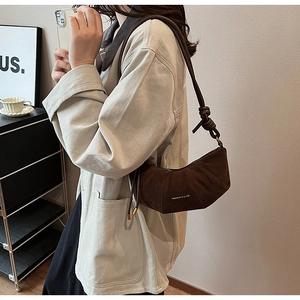 Détail du sac demi-lune en daim marron foncé avec bandoulière en corde nouée et logo