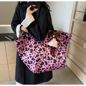 Pink cow print nylon tote bag with cute plush mouse charm shown on model shoulder