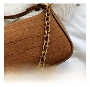 Close-up of brown crocodile embossed shoulder bag with vintage gold metal chain link