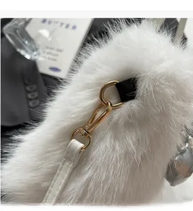 Detail of white plush crossbody bag showing gold metal buckle and premium faux fur texture
