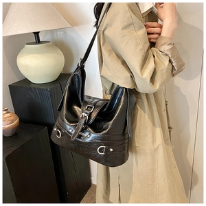 Detail of vintage black PU leather shoulder bag with silver buckles and pleated texture