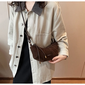 Détail du sac croissant en daim marron foncé avec franges et gravure tendance