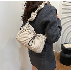 Dettaglio borsa a tracolla in nylon beige con spallina a volant e design arricciato
