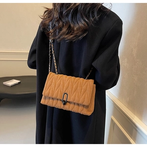 Detail of ginger yellow quilted PU crossbody bag with wave pattern and metal chain strap