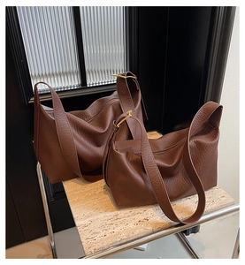 Détail de deux sacs hobo en cuir marron avec texture de lychee sur une surface en travertin