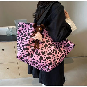 Detail of pink cow print tote bag featuring a cute plush mouse charm and spacious design
