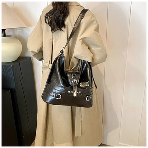 Close-up of black glossy PU leather shoulder bag with silver hardware and buckle detail