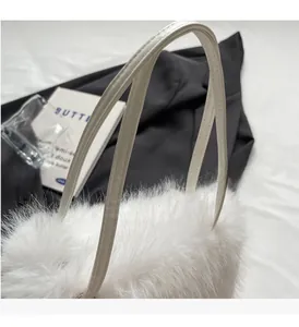 Detailed close-up of fluffy white faux fur texture and leather handles on stylish handbag