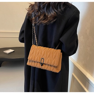 Detail of a brown quilted PU crossbody bag with V-shaped stitching and a chain strap