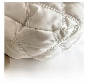 Dettaglio del tessuto in nylon trapuntato avorio con cuciture precise della borsa hobo