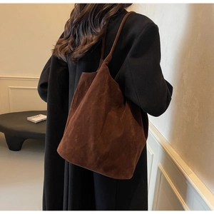 Detail view of a dark brown suede tote bag styled on a shoulder for a vintage look