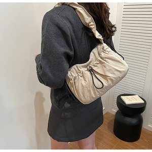 Dettaglio della borsa a spalla in nylon beige con coulisse nera e tracolla larga