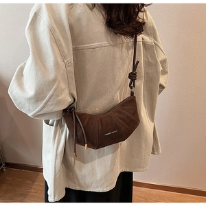 Détail du sac bandoulière croissant en daim marron avec sangle nouée et logo