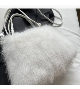 Detailed macro view of soft white plush fabric and elegant pearl charm on the handbag