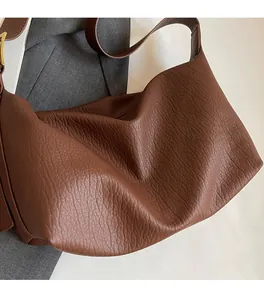 Gros plan d'un sac à bandoulière marron en cuir grainé avec boucle métallique