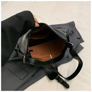 Interior view of black PU shoulder bag showing compartments and brown fabric lining