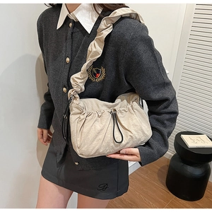 Dettaglio della borsa a tracolla in nylon beige con trama a pieghe e fibbia con coulisse