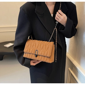 Detail of herringbone quilted faux leather crossbody bag with chic metal chain strap