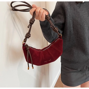 Détail du sac croissant en daim bordeaux avec bandoulière nouée marron et logo doré