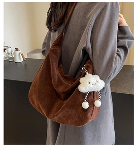 Detail view of large brown suede hobo bag with a white fluffy cloud charm on the side