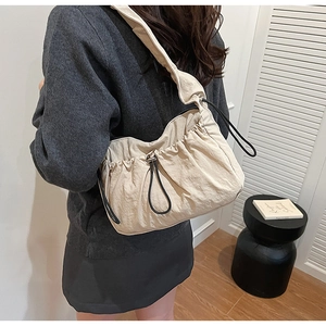 Dettaglio borsa a tracolla in nylon beige plissettato con texture morbida e coulisse nera