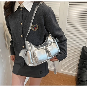 Detail of silver metallic PU shoulder bag with multi-pocket design and utility style finish