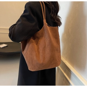 Close-up detail of a large brown suede tote bag with integrated long shoulder straps