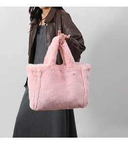 Détail d'un sac cabas en peluche rose montrant la texture douce et les doubles poignées