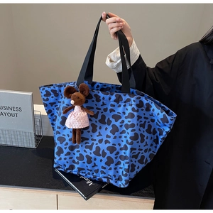 Dettaglio della borsa tote blu con stampa animalier, grande capacità e ciondolo peluche