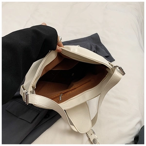 Detail view of the cream PU leather shoulder bag's interior pockets and brown lining