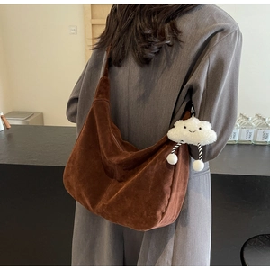 Detail of coffee brown suede hobo bag with wide shoulder strap and cloud plush charm