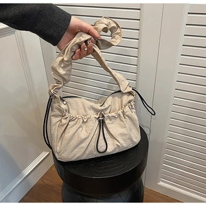 Dettaglio della borsa a spalla in nylon beige con manico a pieghe e dettagli con coulisse