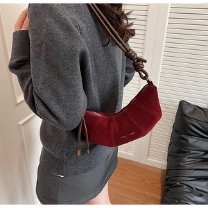 Détail du sac croissant en daim bordeaux avec texte doré et bandoulière nouée
