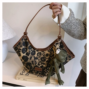 Détail du sac à bandoulière léopard avec bordure en cuir marron et breloque grenouille verte