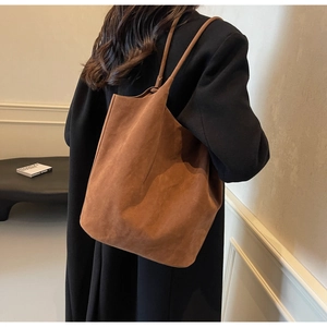 Detail view of large brown faux suede tote bag with slim shoulder straps on model