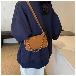 Close-up of brown crocodile pattern shoulder bag with gold chain and brand lettering